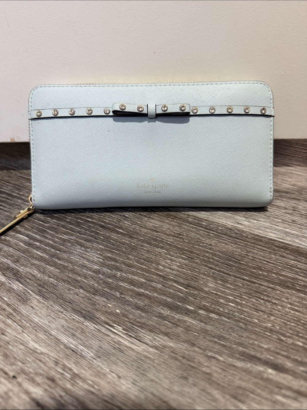 kate spade light blue zip-around wallet with studded bow trim